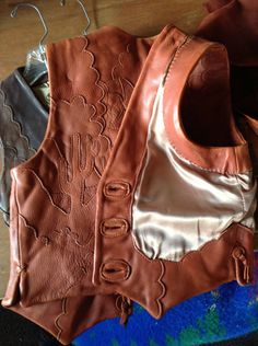 a brown leather vest sitting on top of a wooden floor