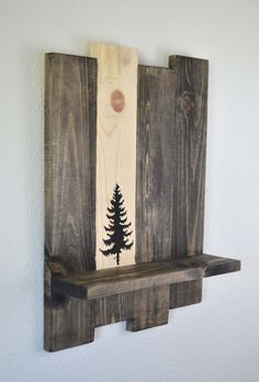 a wooden shelf with a pine tree painted on the front and back of it, hanging from a wall