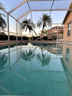 an empty swimming pool with palm trees in the backgroung and clear glass walls