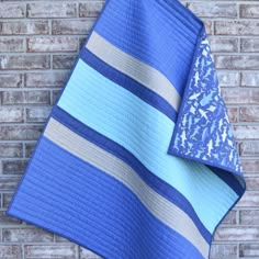 a blue and white quilted blanket sitting on top of a brick wall