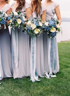 the bridesmaids are all wearing gray dresses with blue flowers in their bouquets