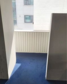 an empty room with blue carpet and white walls, looking out the window at buildings