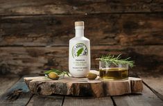 a bottle of olive oil sitting on top of a wooden table next to an olive