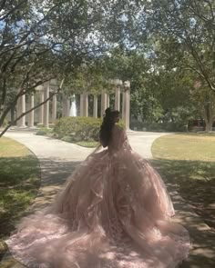 a woman in a pink dress is standing on the sidewalk and looking away from the camera