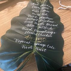 a large green leaf with writing on it sitting on top of a wooden table next to other items