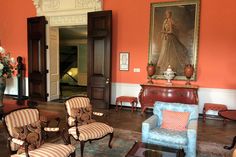 a living room filled with lots of furniture and paintings on the wall above it's doorway