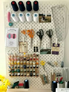 the peg board is organized with scissors, thread, and other crafting supplies on it