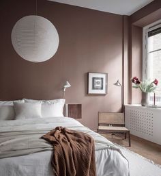 a bedroom with pink walls, white bedding and brown accents on the headboard