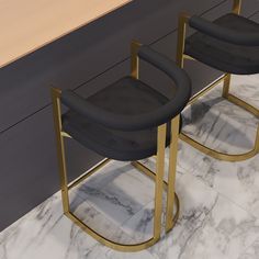 two black chairs sitting on top of a marble floor next to a counter with gold legs