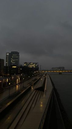 a train traveling down tracks next to a body of water with buildings in the background