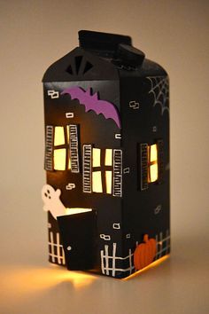 a paper house that is lit up with the lights on and it's halloween decorations