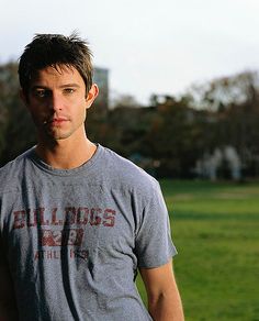 a man standing in front of a green field holding a frisbee and looking at the camera