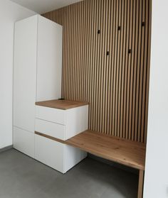 an empty room with white cabinets and wood slats on the wall, along with a wooden bench