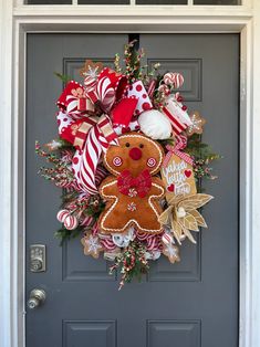 a christmas wreath with gingerbreads and candy canes hanging on a front door