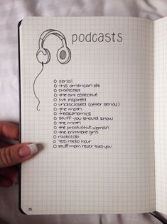 a hand holding an open notebook with headphones on it and the words podcasts written in cursive writing