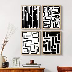 three black and white art pieces hanging on the wall above a wooden dresser in a living room