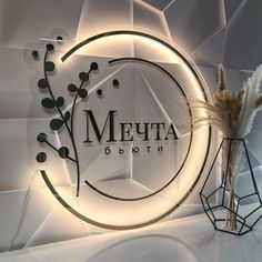 a glass sign with the word meta written on it next to a vase with dried flowers