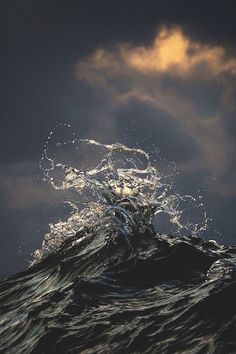 the water is splashing on top of the wave in the ocean, and it appears to be very dark