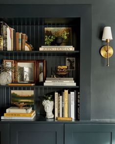 a bookshelf filled with lots of books next to a wall mounted clock and lamp