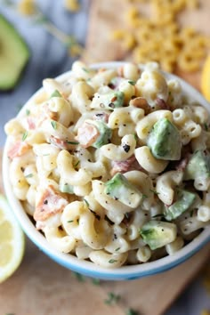 a bowl filled with macaroni salad next to sliced lemons