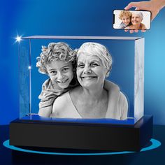 a woman taking a photo with her cell phone in a glass case that has an image of two women on it