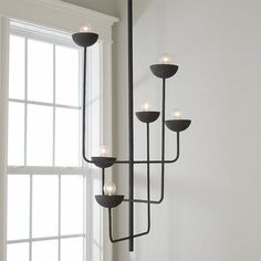 a black chandelier with five lights hanging from it's sides in front of a window