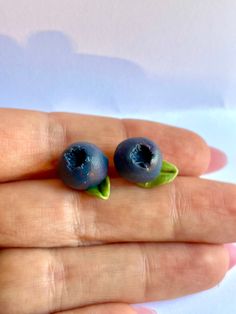 two tiny blueberries with green leaves on top of each other in someone's hand