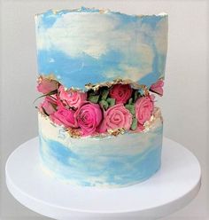 a blue and white cake with pink flowers on top