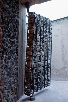 a metal rack filled with bread on top of a cement floor next to a brick wall