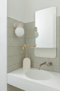 a white sink sitting under a bathroom mirror next to a wall mounted faucet