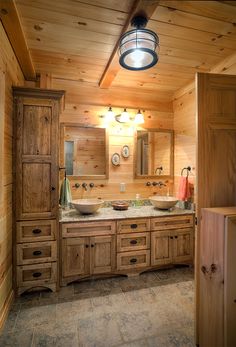 a bathroom with two sinks and wooden cabinets in the corner, along with a light fixture