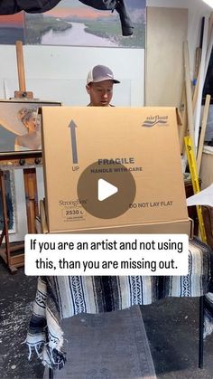 a man sitting in front of an easel holding a sign that says if you are artist and not using this, than you are missing out