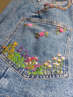 a pair of jeans with embroidered flowers on them