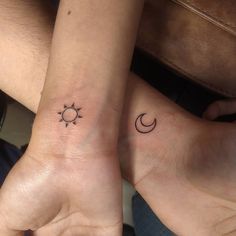 two people holding hands with tattoos on their wrists and one has a sun and moon