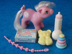 a pink pony toy next to a baby bottle and other toys on a blue background