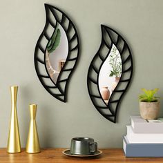 two mirrors on the wall above a table with vases and books in front of them