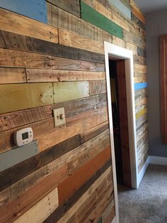 a room with wood planks on the wall and an open door to another room