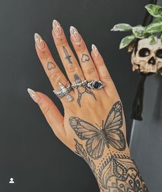 a woman's hand with tattoos and rings on it