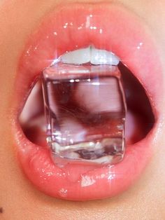 a woman's mouth with an ice cube in it