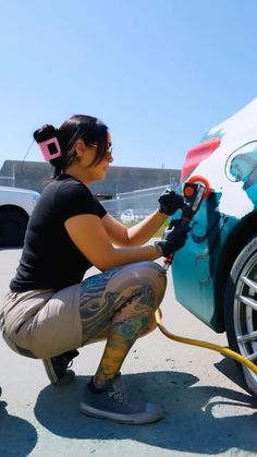 a woman is painting the side of a car