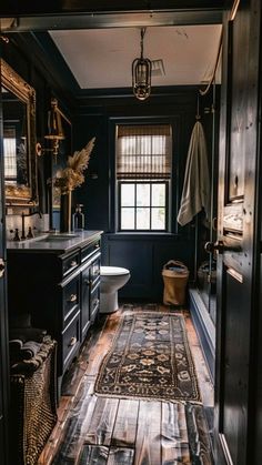 a bathroom with black walls and wooden floors, an area rug on the floor that matches the toilet