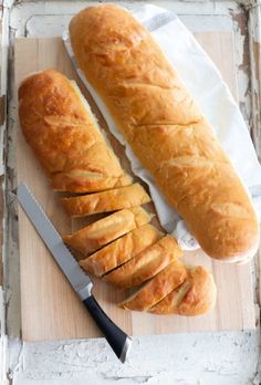 two loaves of bread sitting on top of a cutting board next to a knife