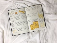 an open notebook on top of a bed with white sheets and yellow stickers attached to the pages