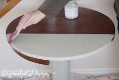 a person using a brush to paint a table with white and brown trim on it