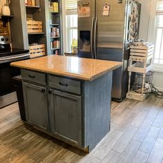 a kitchen with an island in the middle and stainless steel appliances on the other side