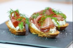 two pieces of bread topped with prosciutto, cheese and garnish