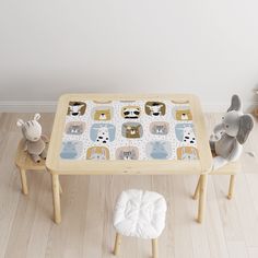 a child's wooden table with two stuffed animals sitting on top of it and an animal toy next to the table