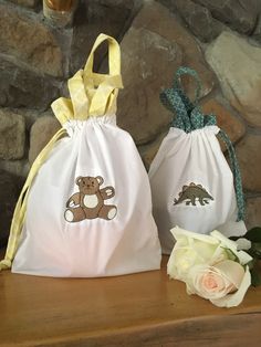 two bags with teddy bears on them sitting on a table next to flowers and a stone wall