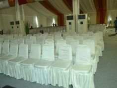 rows of white chairs are lined up in a banquet hall