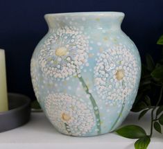 a blue vase sitting on top of a table next to a candle and some plants